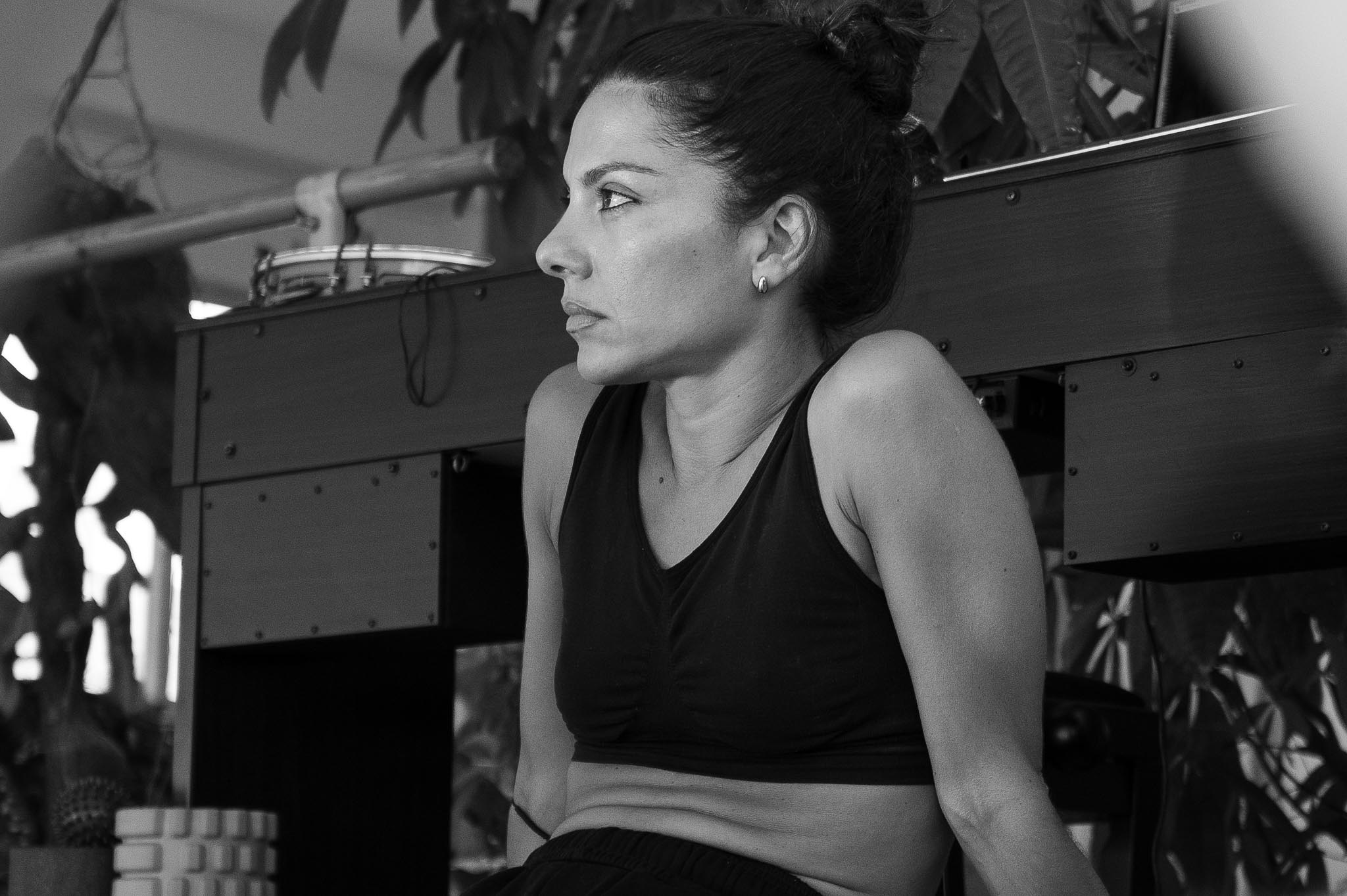 Vilelmini sitting during a pause in the workshop, leaning against the desk with a focused, contemplative expression.