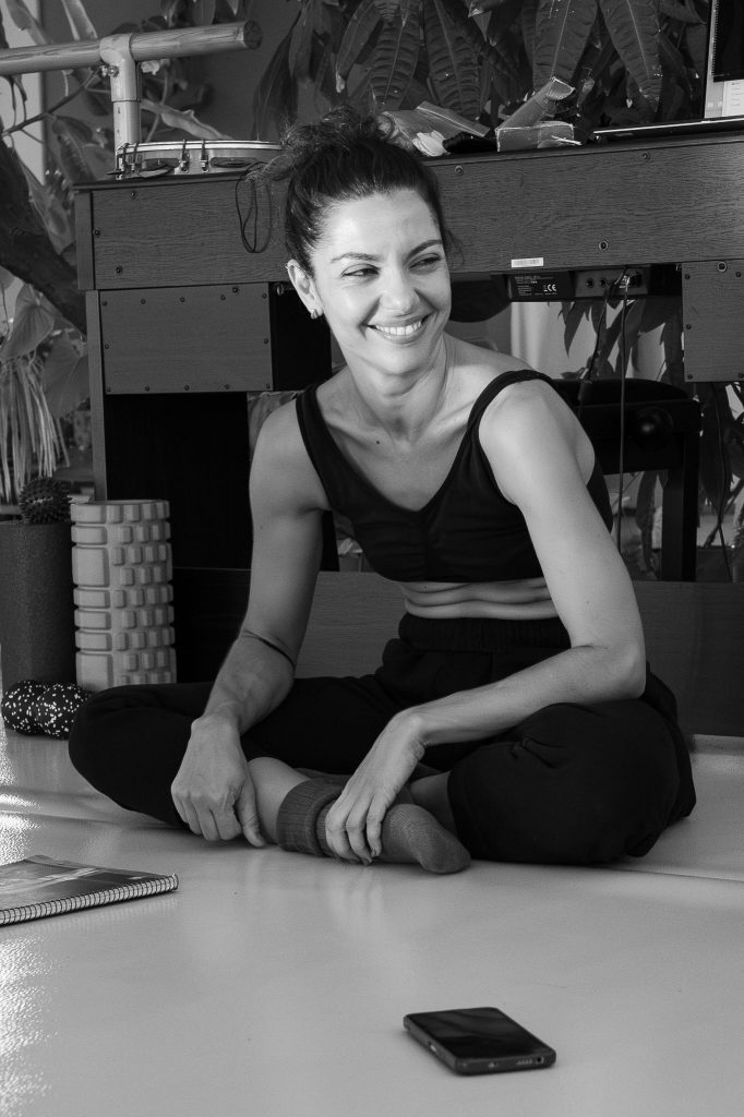 Vilelmini sitting on the floor during the workshop, smiling warmly in a relaxed moment.